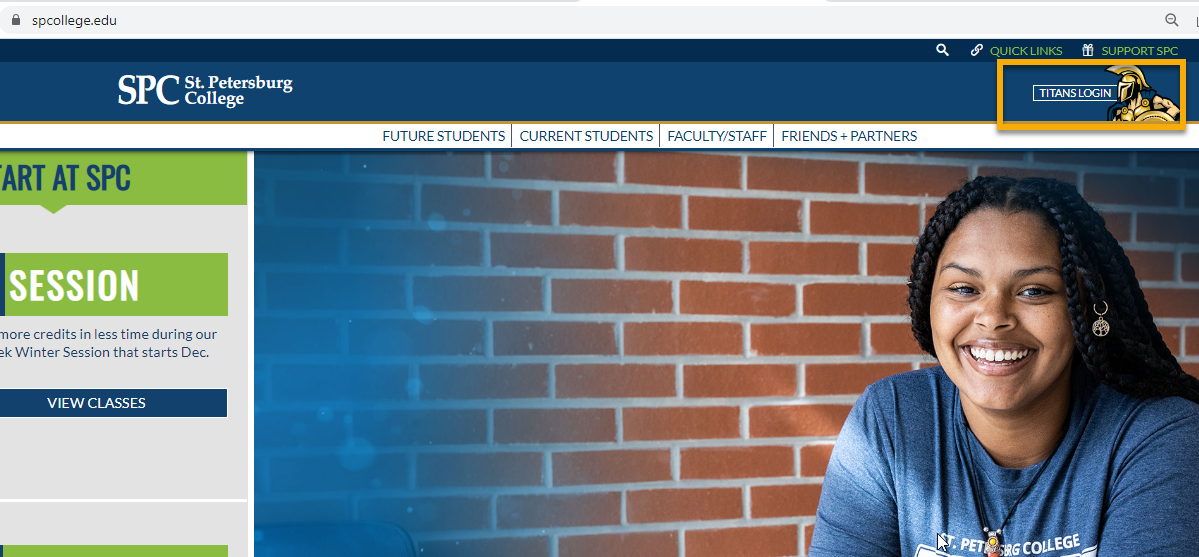 Student smiling in front of a brick wall.
