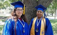 Two graduates in blue caps and gowns.